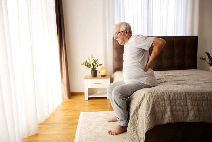 Person som håller sig om ryggen vid ryggvärk